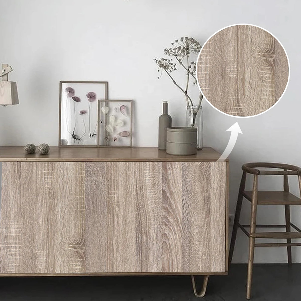 A wooden cabinet with a wood grain finish displays framed art and decorative items on a white wall.