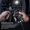 A hand holds a smartphone with an inspection camera connected to a cable, positioned near a car wheel for diagnostics.