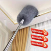 A silver extendable microfiber duster with a fluffy gray head is shown hanging from a ceiling fixture.