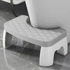A white ergonomic non-slip toilet squat stool with a diamond-patterned seat is shown on a glossy floor.