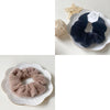 A pair of black plush coil hair ties displayed on a white plate, with a gold star decoration nearby.
