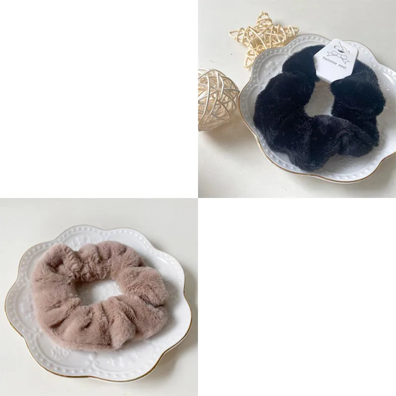 A pair of black plush coil hair ties displayed on a white plate, with a gold star decoration nearby.