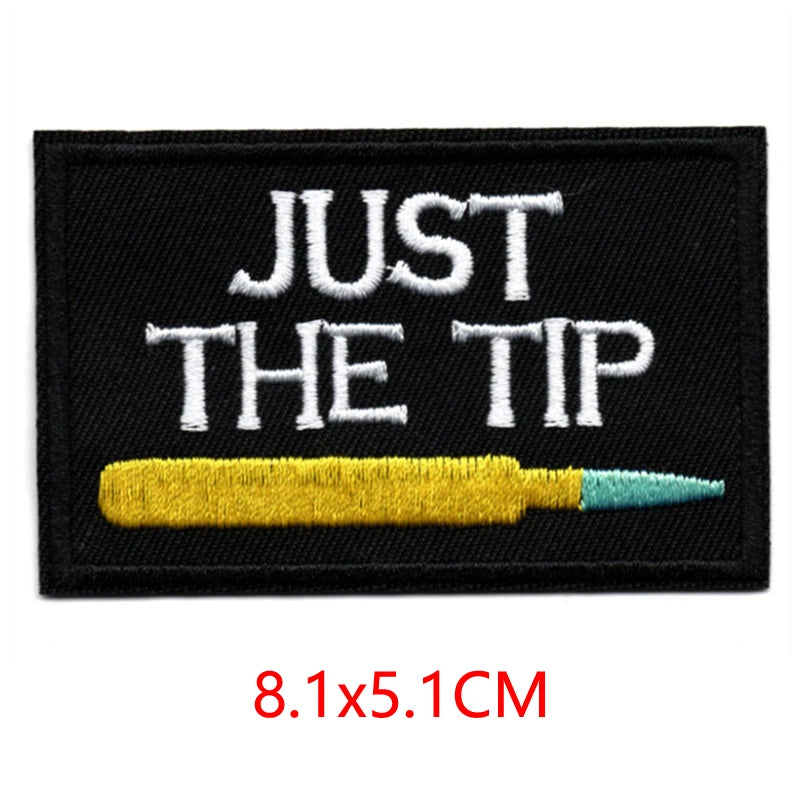 Black embroidered iron-on letter patch with white text JUST THE TIP and a yellow pencil on it.