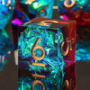 A close-up of a black polyhedral dice set with iridescent blue resin and gold accents, resting on a dark surface.