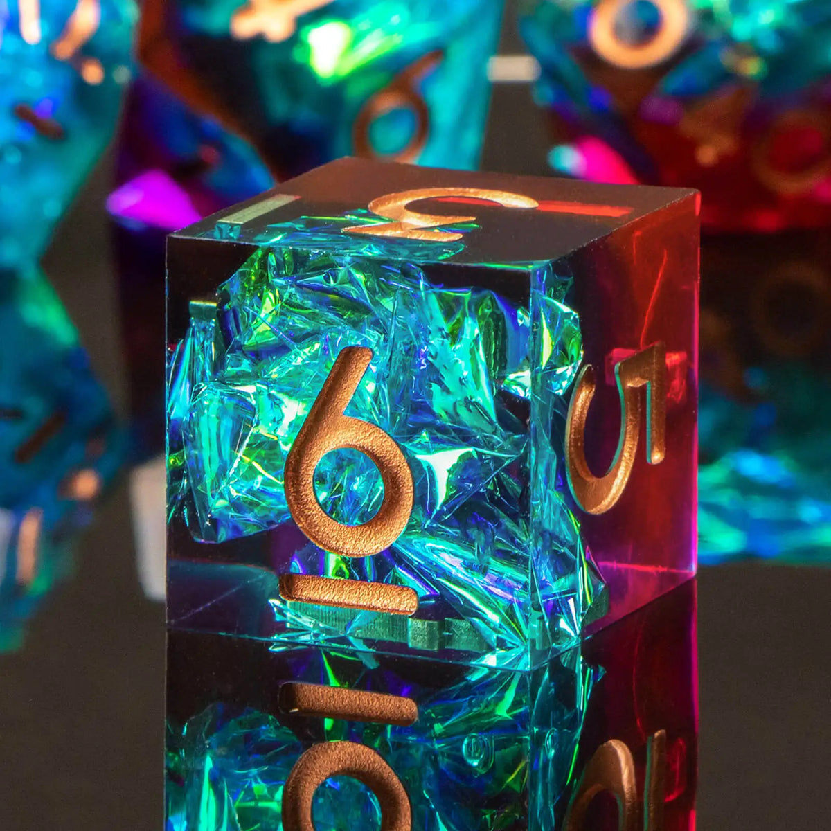 A close-up of a black polyhedral dice set with iridescent blue resin and gold accents, resting on a dark surface.