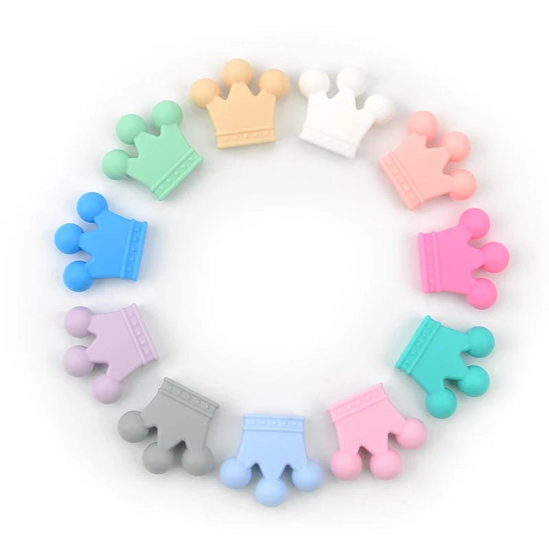 A collection of colorful food-grade silicone crown beads in various pastel colors arranged in a circle.