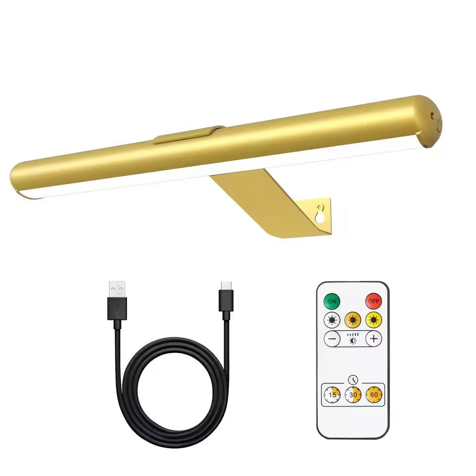 A gold-colored picture light fixture with a long bar and a separate remote control unit and power cord.