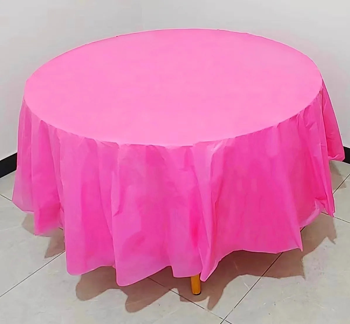 A vibrant pink disposable round tablecloth is displayed on a table.