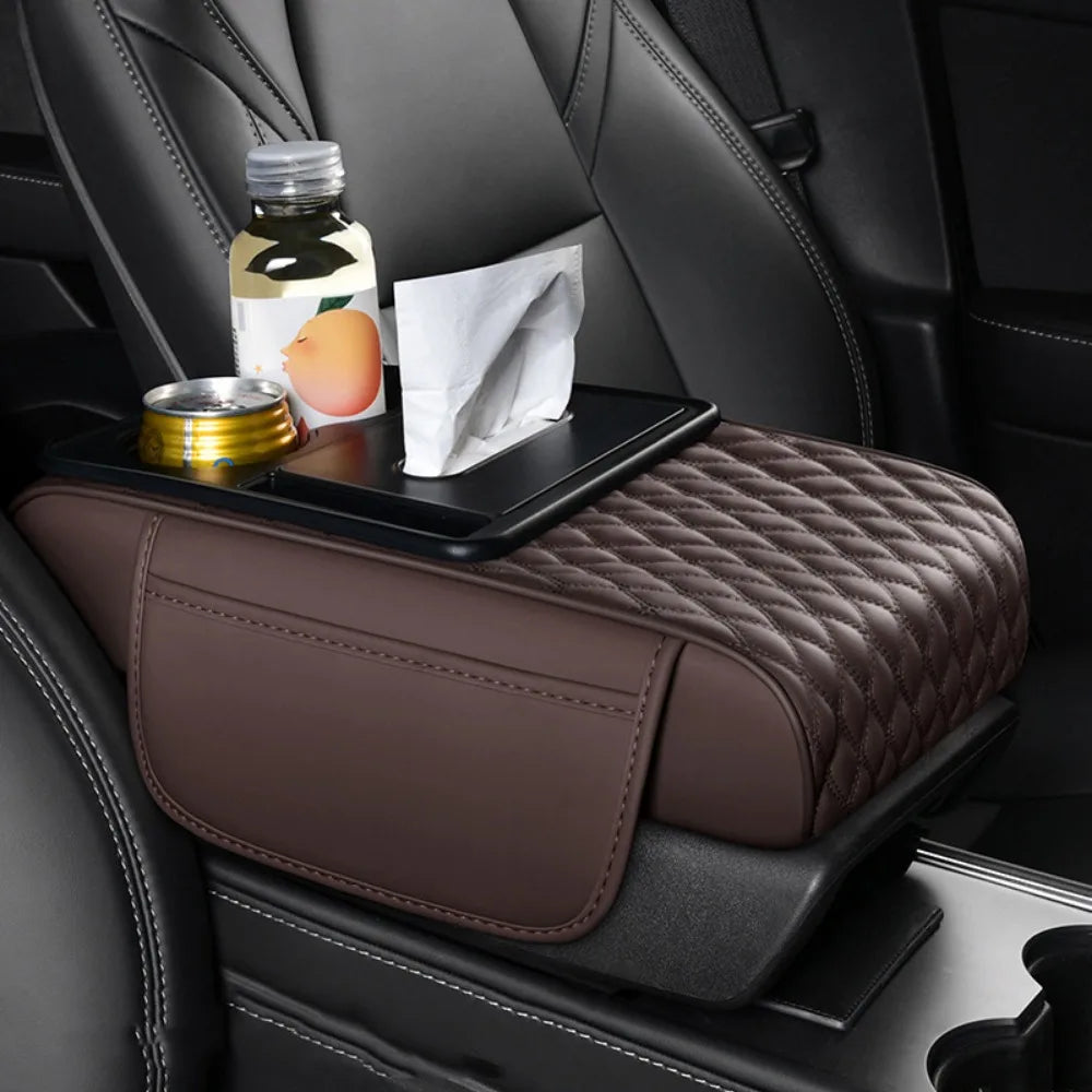 A dark brown quilted car armrest cushion with storage and cup holders is placed on a black car seat.