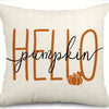 A beige pillow cover featuring the word hello in orange script with a small pumpkin illustration.
