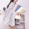 A woman is holding a light gray coconut milk strip bath towel in a casual pose against a white background.