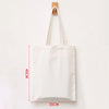 A white reusable canvas shopping tote bag hanging on a wooden hanger.