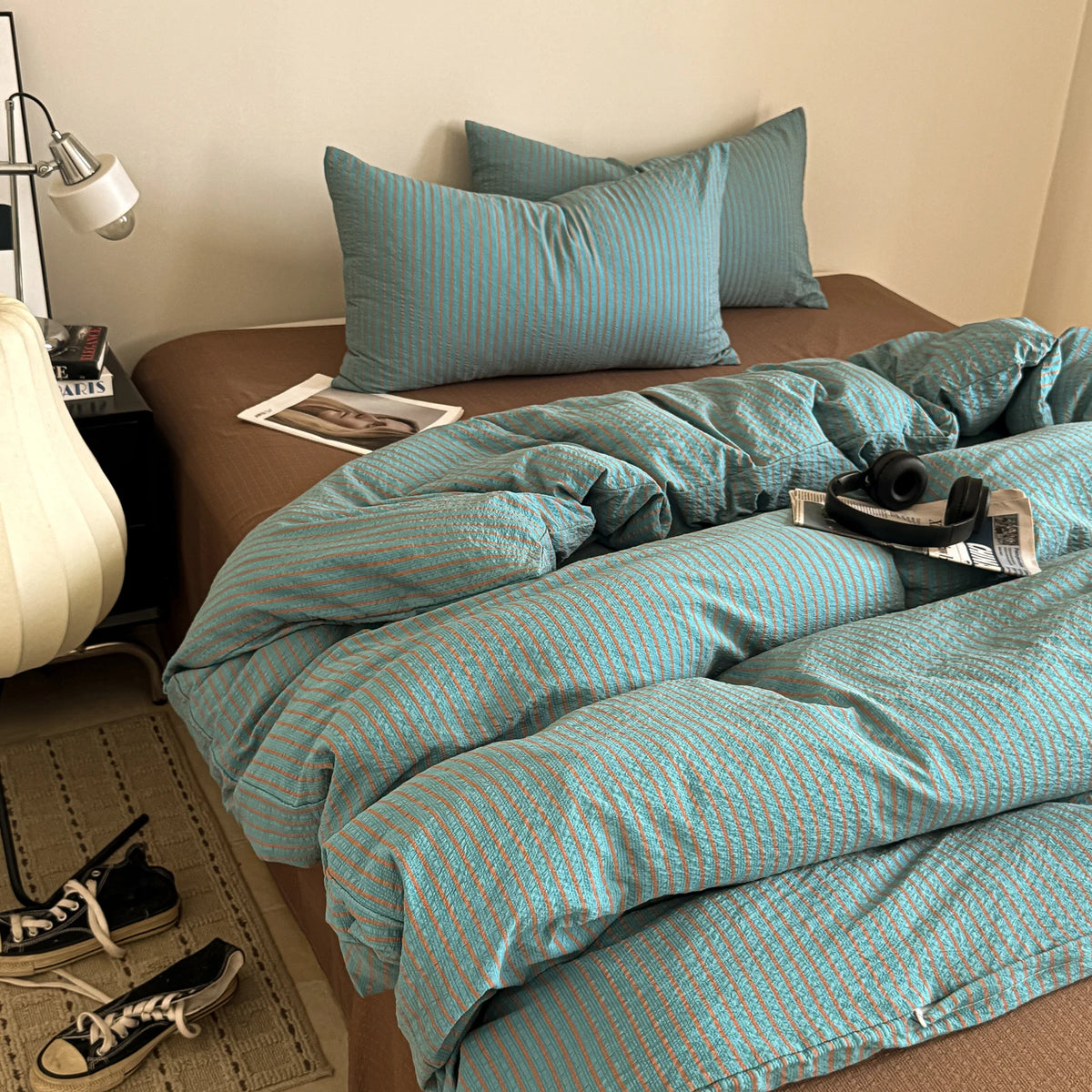 A teal striped duvet cover set with matching pillowcases is displayed on a bed.