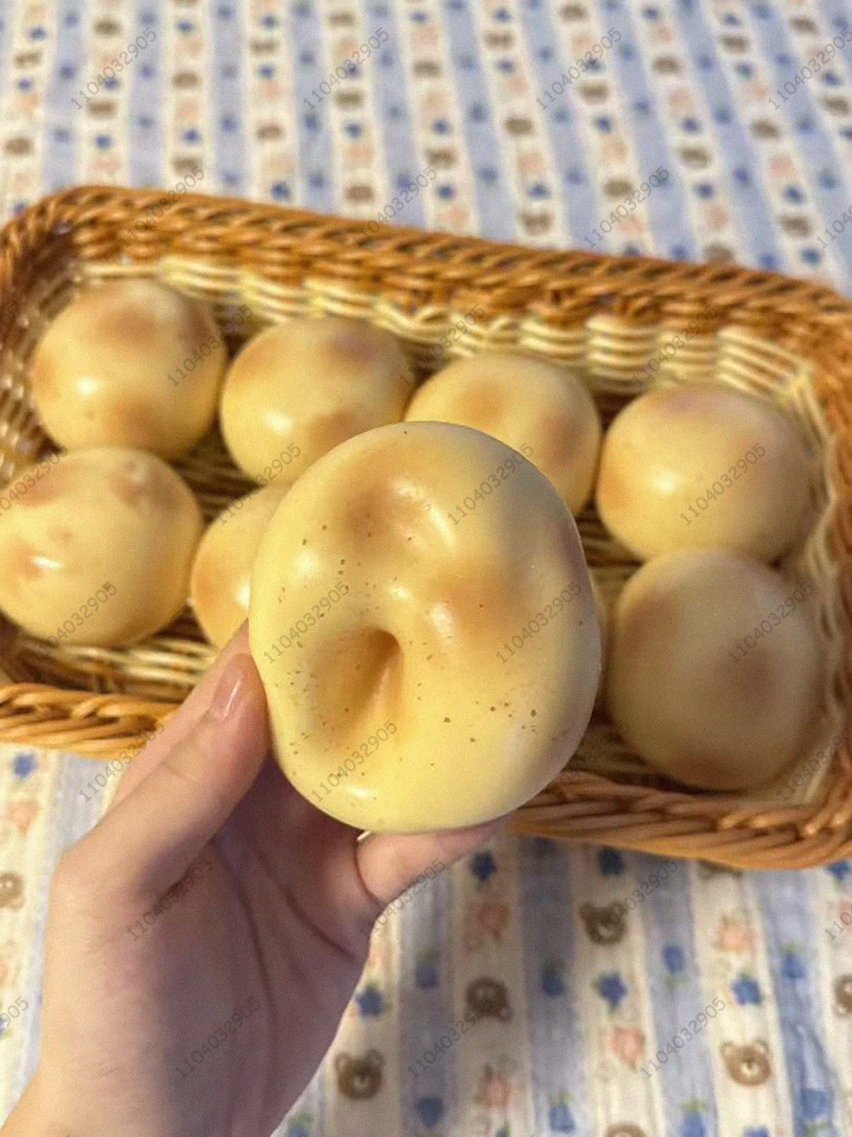 Eine Hand hält einen hellgelben knackigen Kartoffel-Stressball-Fidget-Spielzeug in einem geflochtenen Korb.