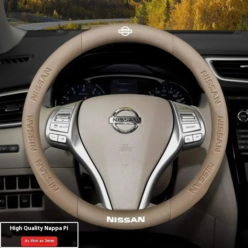 A close-up view of a beige Nissan steering wheel with carbon fiber accents and a leather grip.