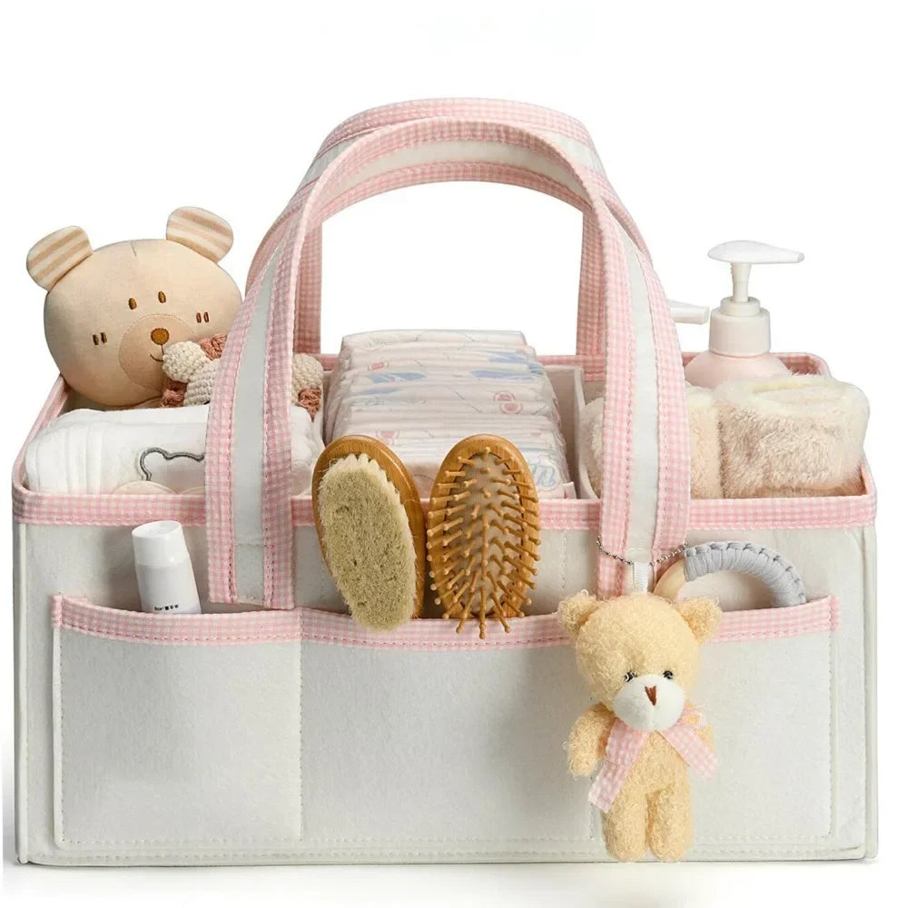 A pink and white floral diaper organizer bag filled with baby grooming tools and soft toys.