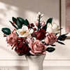 A bouquet of pink and white roses with dark green leaves arranged in a white vase.