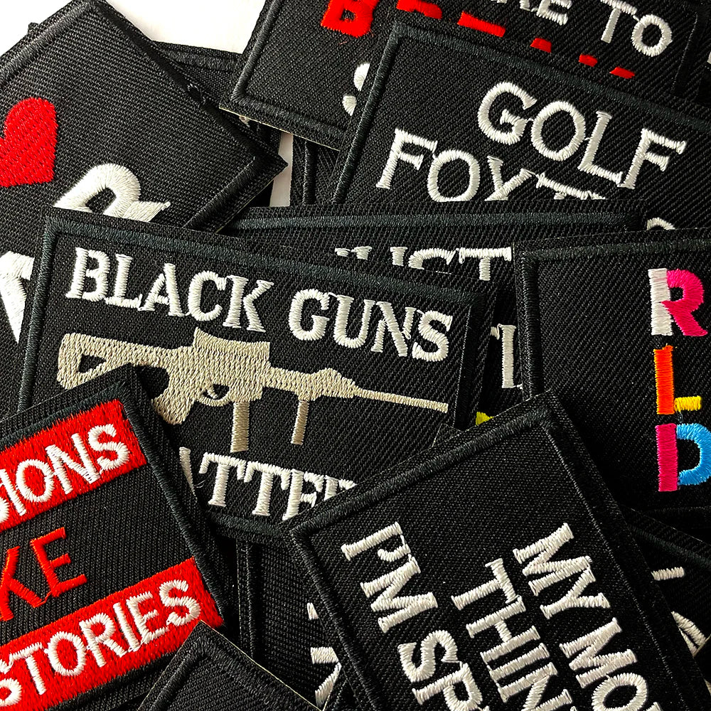 A collection of black embroidered iron-on patches featuring text like BLACK GUNS and GOLF.