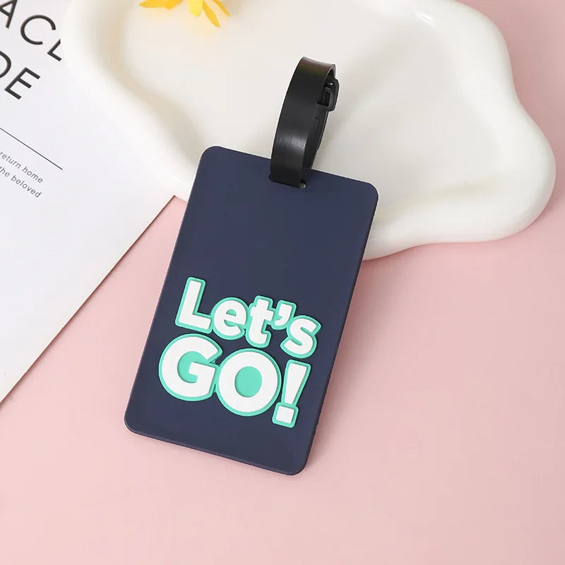 A dark blue silicone luggage tag with the text Let's GO! in light green lettering, attached to a black strap.