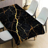 Black gold marble waterproof tablecloth spread over a dining table with white chairs.