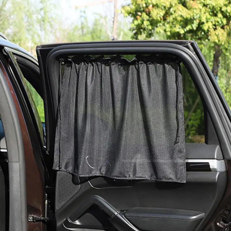 A black universal car side window sunshade is installed in a vehicle door frame.