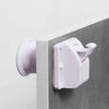 A close-up view of a white magnetic cabinet lock with a keyhole and a plastic lever, mounted on a gray cabinet frame.