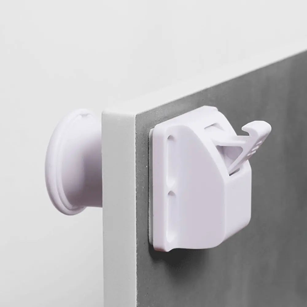A close-up view of a white magnetic cabinet lock with a keyhole and a plastic lever, mounted on a gray cabinet frame.