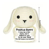 A handmade white bunny crochet doll with a positive message card.