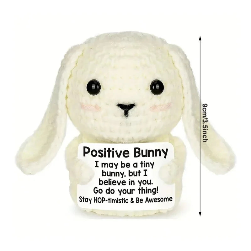 A handmade white bunny crochet doll with a positive message card.