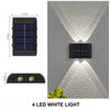 A black solar powered wall light with four LED white lights casting an upward and downward illumination on a gray textured wa