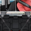 Black leather seat belt covers with custom logo accents installed in a car interior.