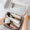 A hand opens a leopard print toiletry bag revealing various skincare products inside.