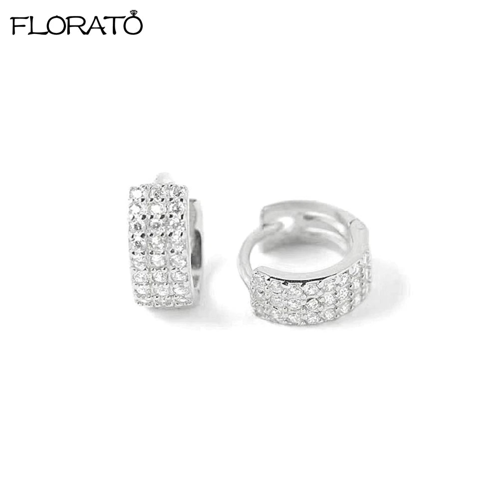A pair of minimalist cubic zirconia huggie hoop earrings shown against a white background.