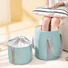 A light blue collapsible foot bath tub with a storage bag is shown next to a person using it.
