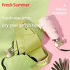 A pink folding umbrella with a green handle and UV protection features is shown against a light background.