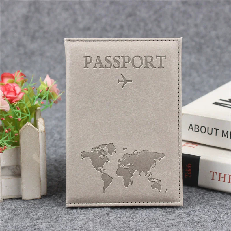A beige leather passport holder featuring a silver embossed world map and an airplane symbol.