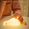 A hand is pinching a white silicone duck night light, illuminating the surface.