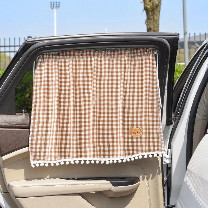A brown and white checkered sun shade curtain is installed in the window of a car.