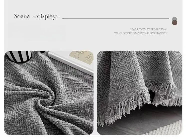 A close-up of a gray herringbone chenille sofa throw with tassel edges draped on a surface.