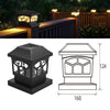 A black solar post cap light fixture with a warm LED illuminates a wooden fence or deck.