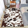 A faux cowhide pattern area rug in brown and white spots placed on a wooden floor.
