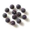 A scattering of dark purple crystal clay round beads for DIY jewelry and craft projects
