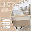 A woven cotton rope storage basket in beige and cream sits on a rug next to a bed.