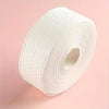 A roll of white lint-free cotton rounds for nail care against a pink background.