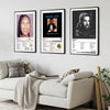 Three framed canvas prints featuring Drake album art and portraits displayed on a gray wall above a white sofa.