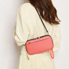 A woman is holding a pink waterproof passport and document organizer wallet against a light beige jacket.