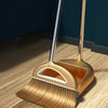 A golden broom and dustpan set with a floor wiper resting on a wooden floor.
