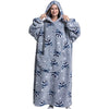 A woman wearing a gray oversized wearable blanket hoodie with a hood and sleeves.