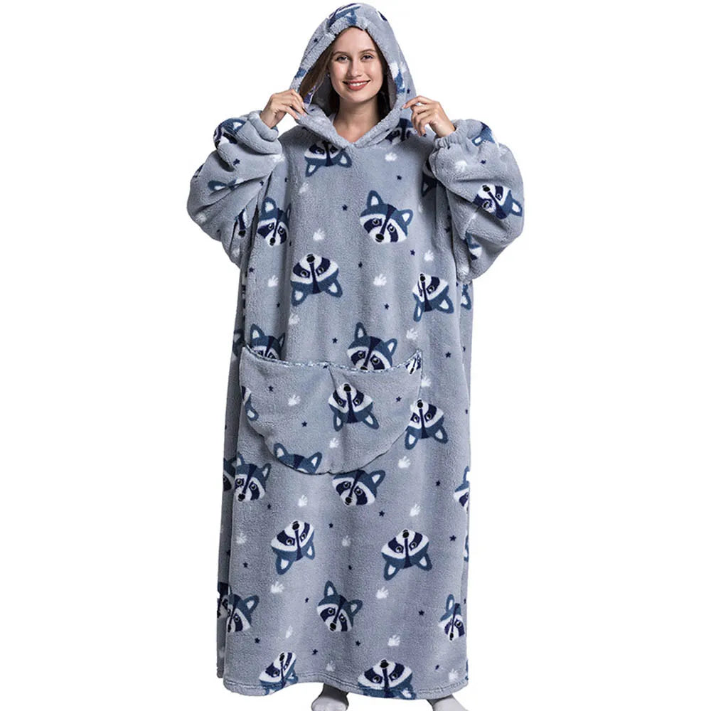 A woman wearing a gray oversized wearable blanket hoodie with a hood and sleeves.