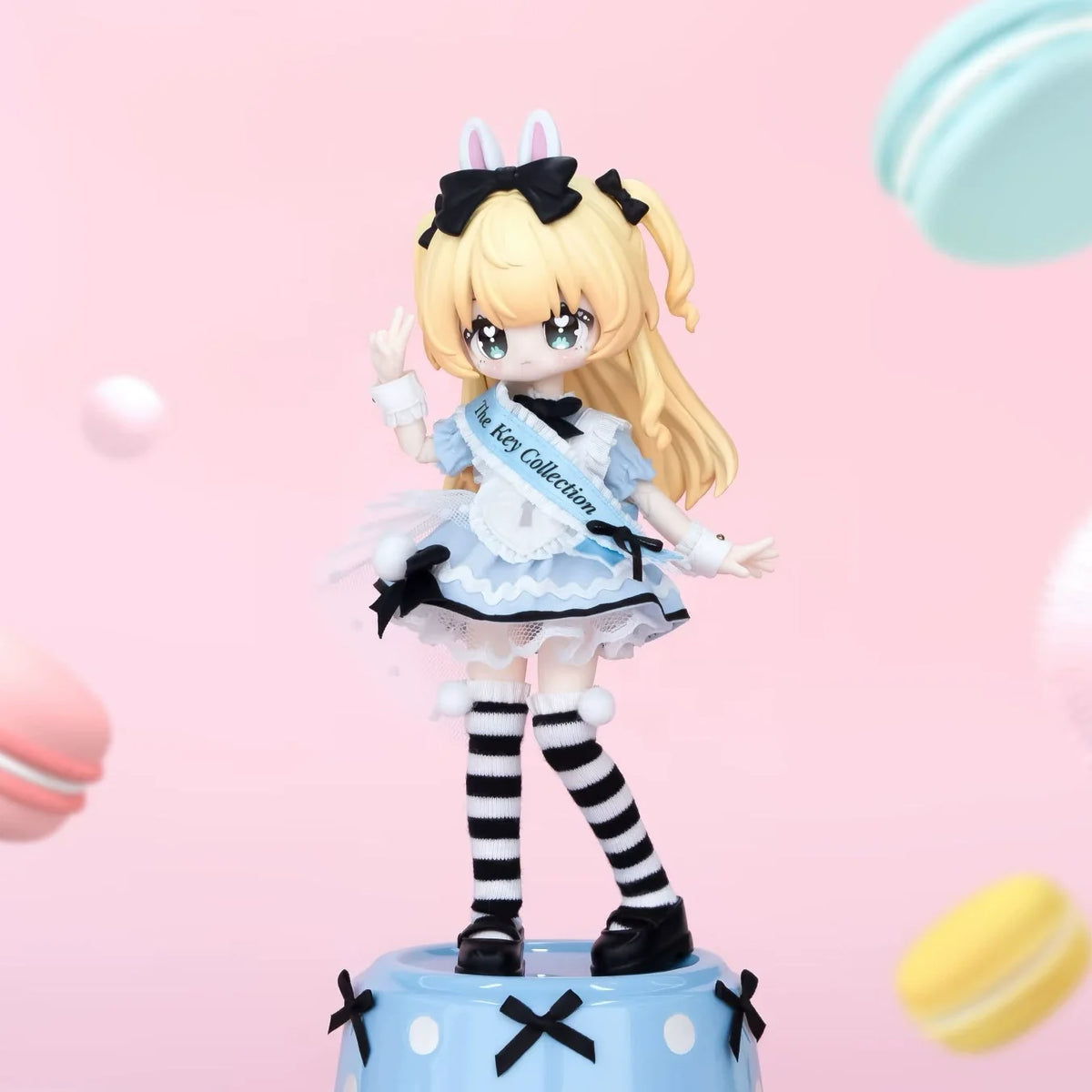 A blonde anime-style collectible figurine with black hair and a white dress featuring stripes and bows.